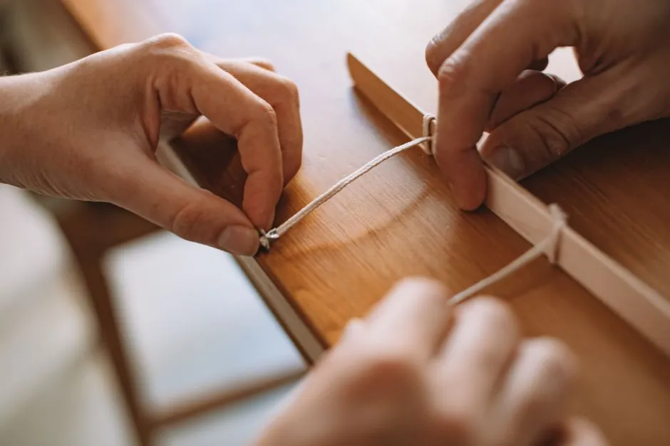 Close-up of hands knotting cord by hand